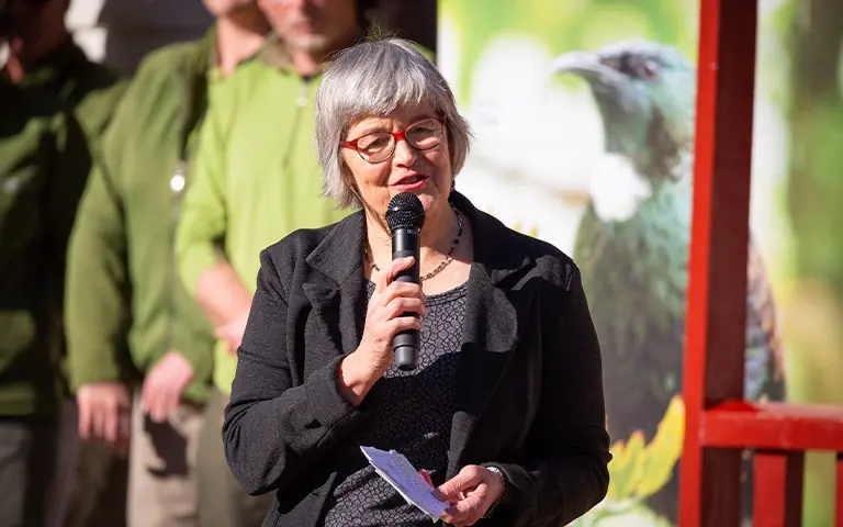 Photograph of Minister Sage holding a microphone.